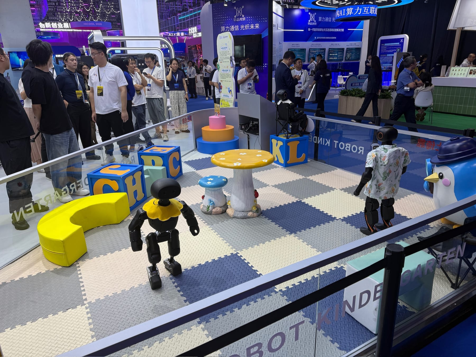 Small humanoid robots on a foam play mat inside an exhibit labeled Robot Kindergarten, at the HICOOL summit in Beijing.